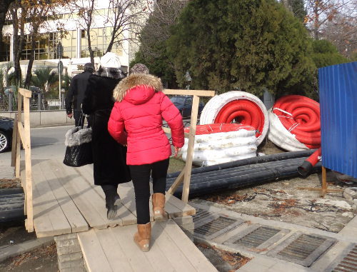 Жители Сочи перебираются через канавы, прорытые вдоль Набережной, по деревянным мосткам. Сочи, 29 декабря 2012 г. Фото Светланы Кравченко для "Кавказского узла" 