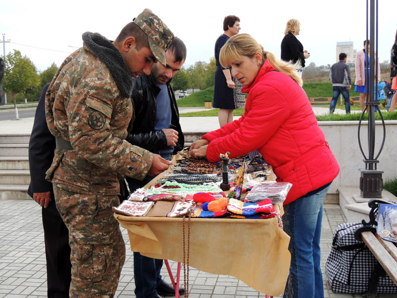 Лиана показывает покупателям сувениры.